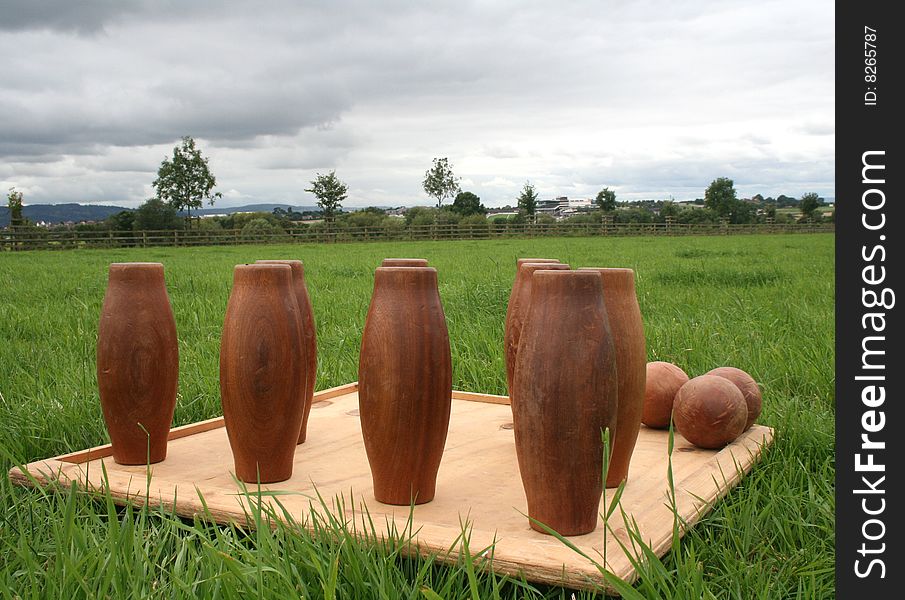 A set of wooden skittles are set up outdoors, ready to play. A set of wooden skittles are set up outdoors, ready to play.