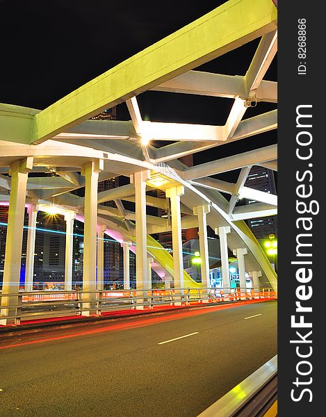 A view of a bridge with cars zooming past at night, and the central business district in the background. A view of a bridge with cars zooming past at night, and the central business district in the background.