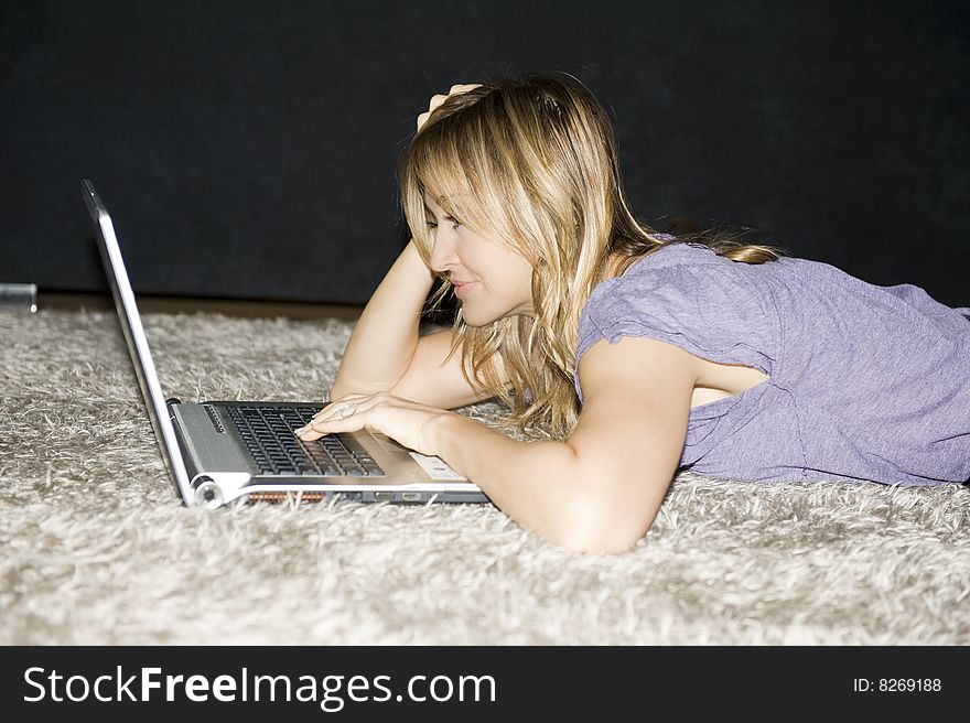 Woman laying down and working on a laptop computer at home. Woman laying down and working on a laptop computer at home