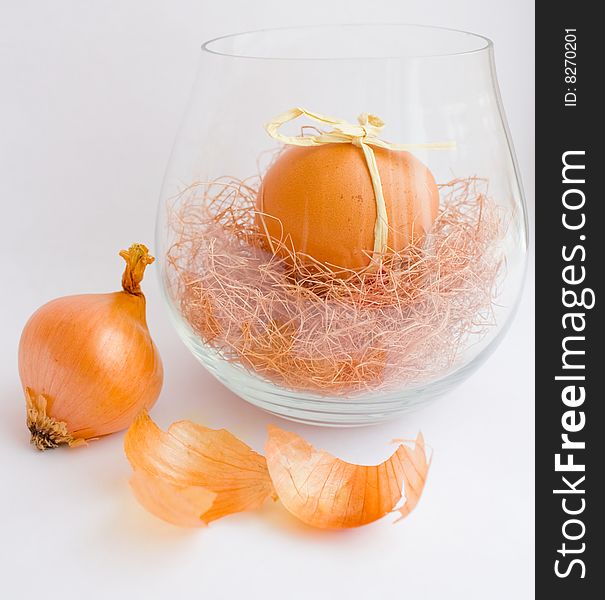 Onion and painted egg in glass vase. Onion and painted egg in glass vase