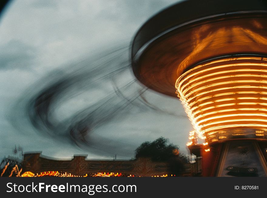 Fairground motion pic with chairplane ride. Orange motion blur against leaden sky. Fairground motion pic with chairplane ride. Orange motion blur against leaden sky