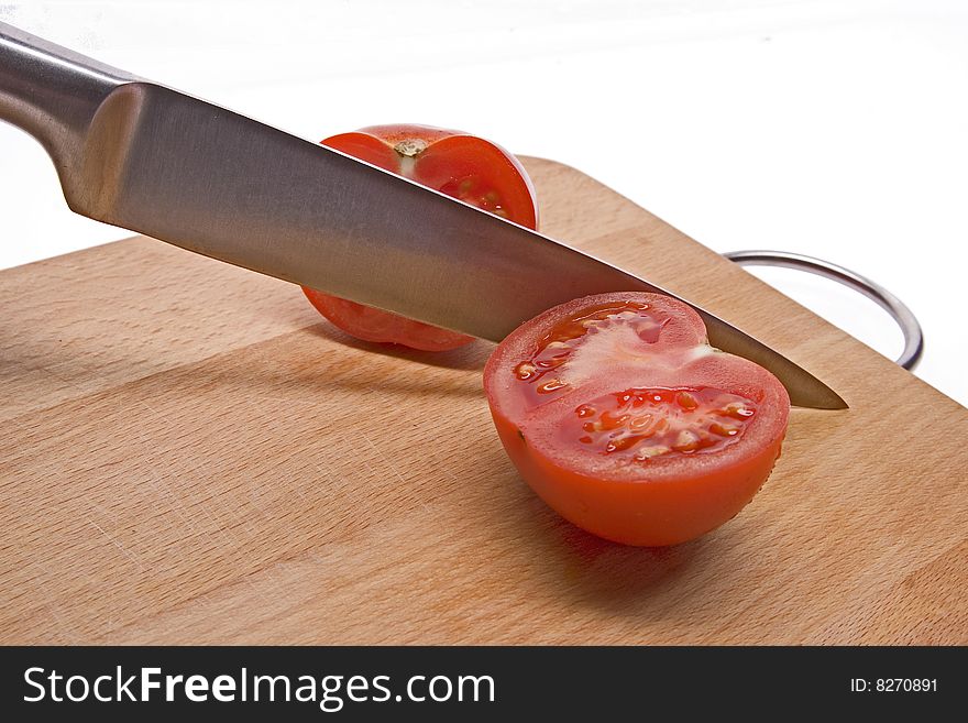 A sliced tomato on the kitchen board. White background. A sliced tomato on the kitchen board. White background.
