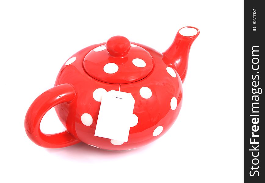 Ceramic teapot of red color with a tea on a light background.