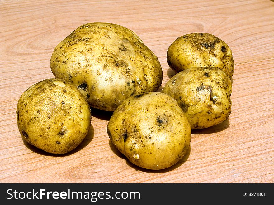 Raw potatoes of various sizes on a wooden table. Raw potatoes of various sizes on a wooden table