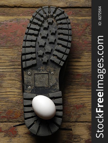 Riffled boot and egg composition on a wooden floor. Riffled boot and egg composition on a wooden floor