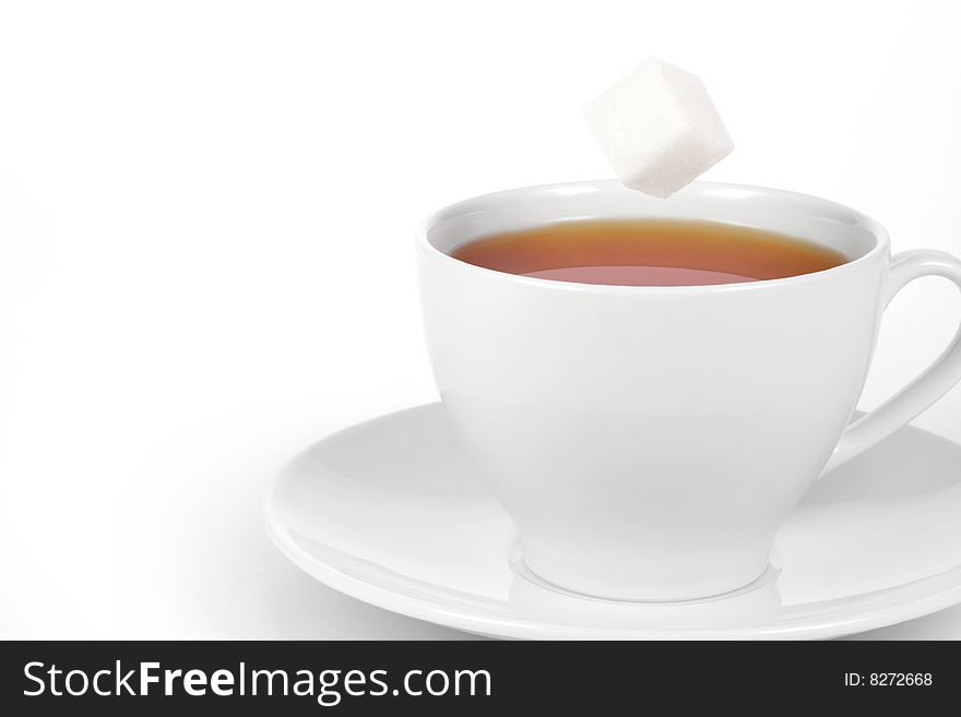 Cup of tea with sugar cube on a white background