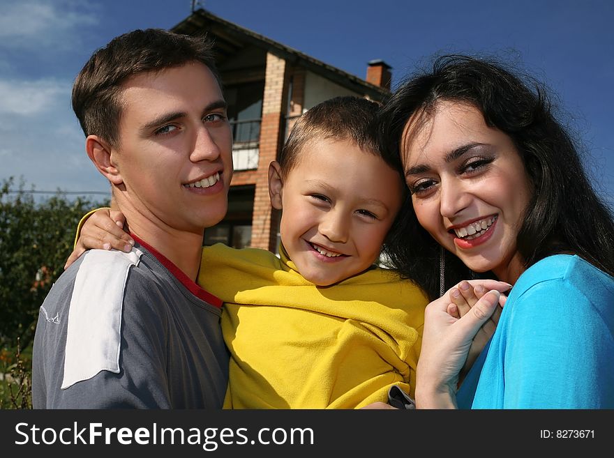 Young happy family beside their new house