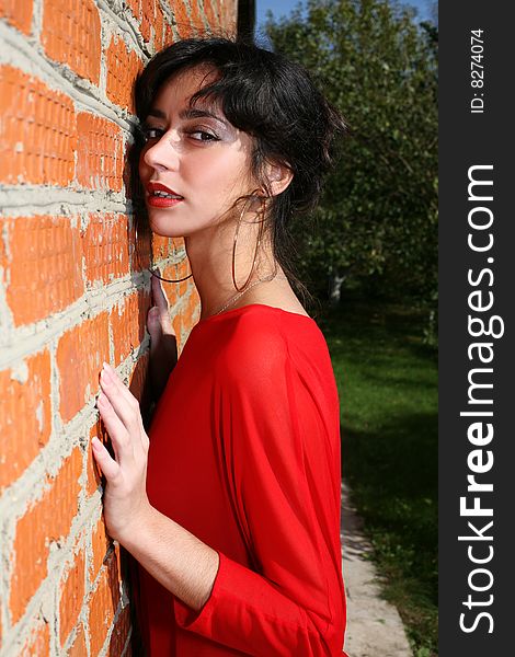 Lovely girl beside wall in red dress