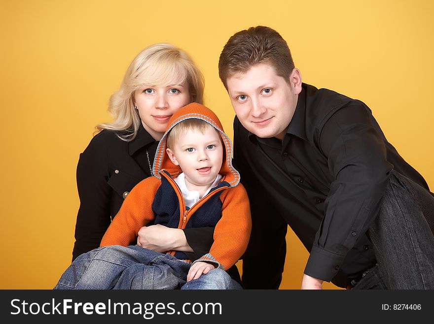 Happy family with baby on yellow background. Happy family with baby on yellow background
