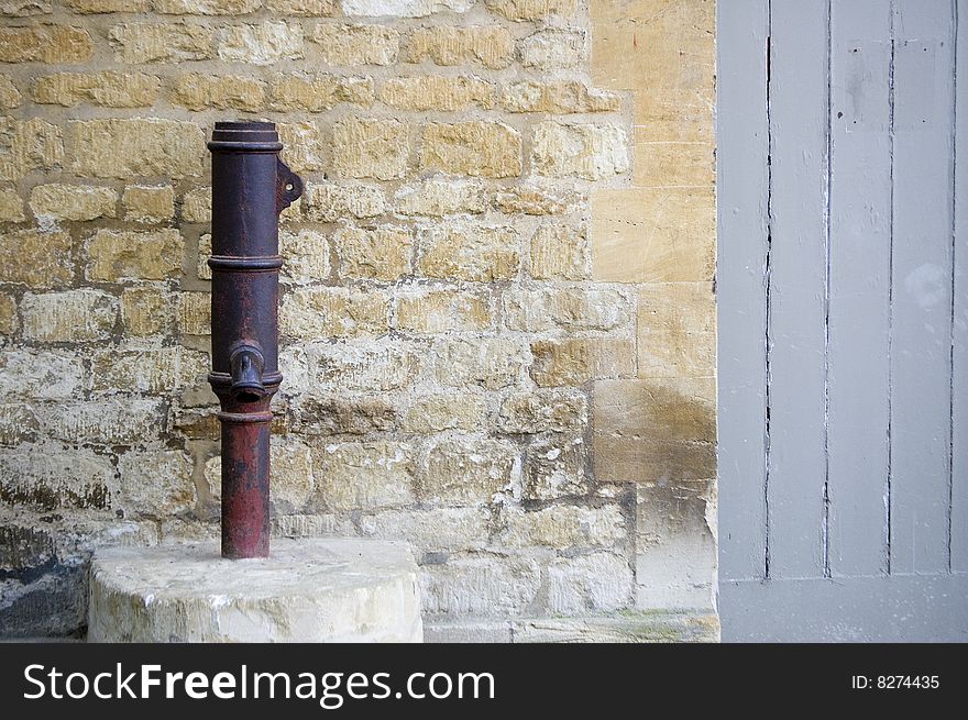 An old hand water pump set against a brick wall. An old hand water pump set against a brick wall