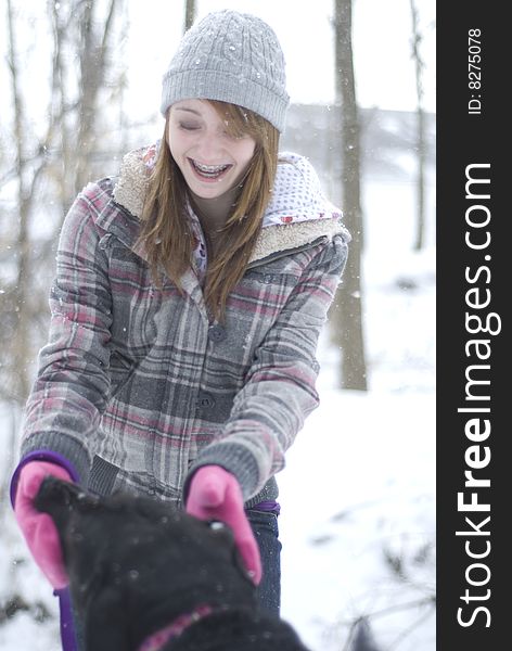 Teen girl playing in snow with black lab dog. Teen girl playing in snow with black lab dog