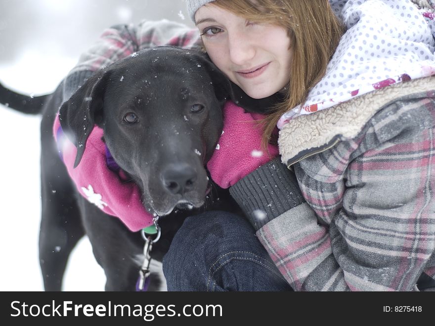 Teen girl sitting in snow with black lab dog. Teen girl sitting in snow with black lab dog