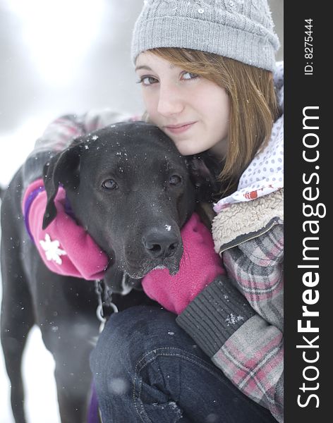 Teen girl sitting in snow with black lab dog. Teen girl sitting in snow with black lab dog