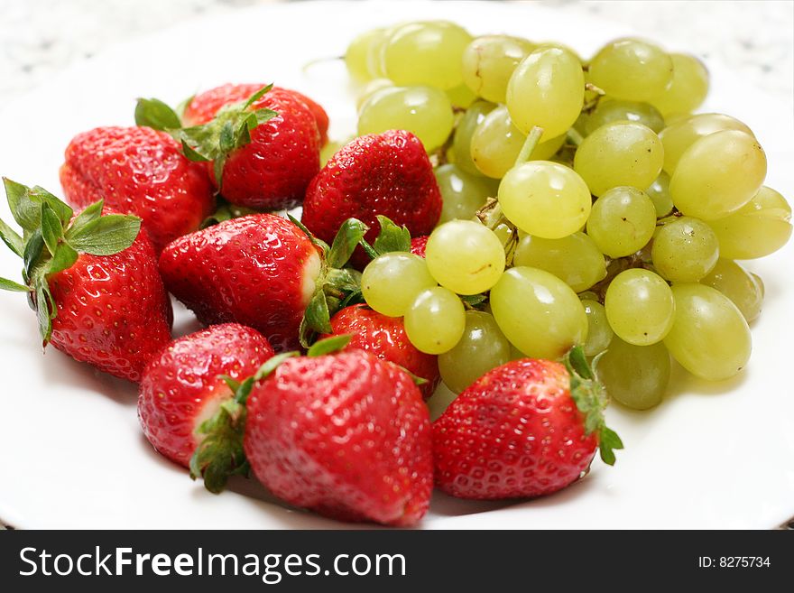 Grape and strawberry over white dish isolated