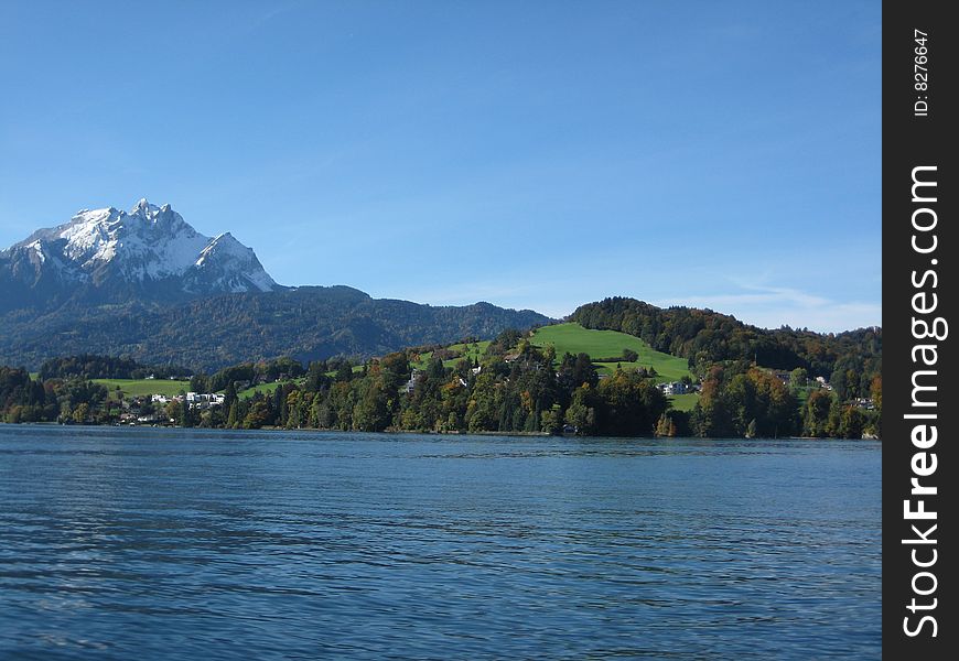 Snow capped mountain with a lush green hill side in front of it on lake Luzern, Switzerland. Snow capped mountain with a lush green hill side in front of it on lake Luzern, Switzerland