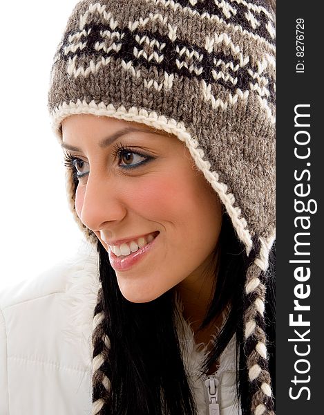 Side pose of smiling woman wearing woolen cap against white background