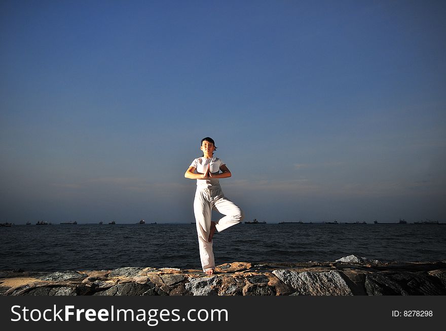 Picture of a woman doing yoga by the beach.