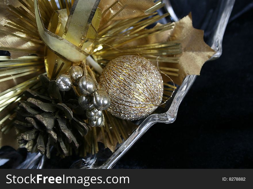 Variety of gold coloured christmas decorations in a glass bowl