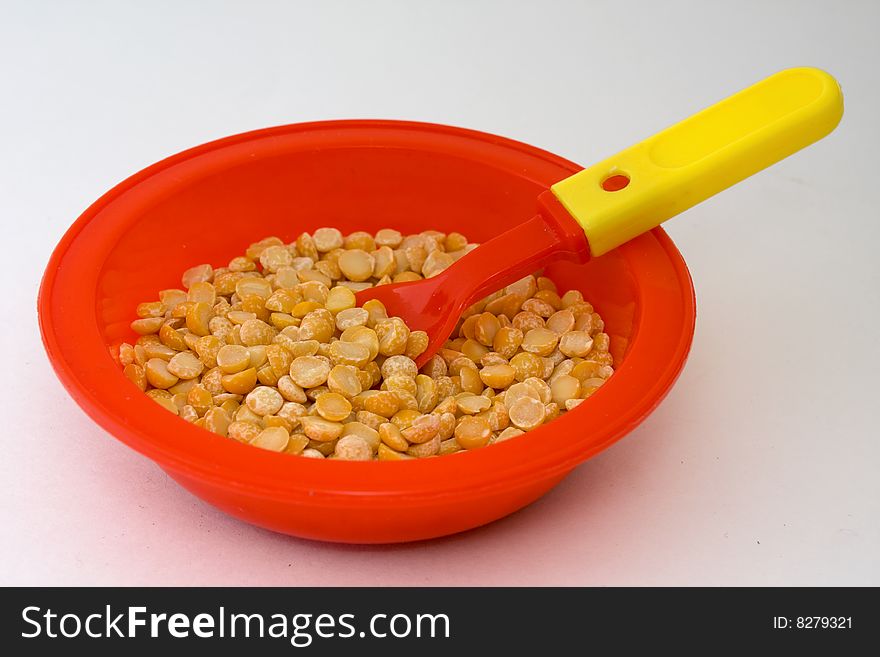 Red bowl filled with peas and inserted a spoon. Red bowl filled with peas and inserted a spoon