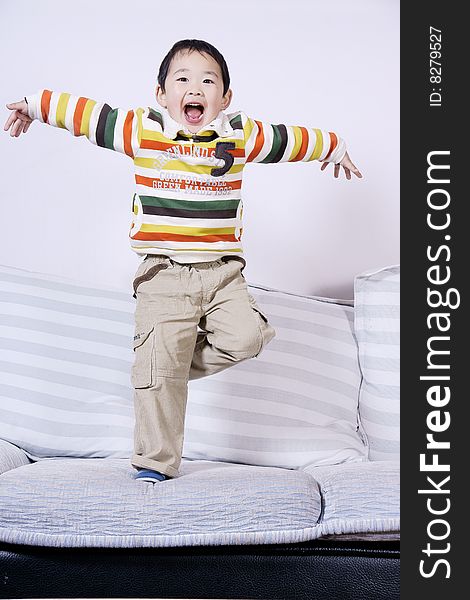 A picture of a little chinese boy playing roles and having great fun on sofa at home