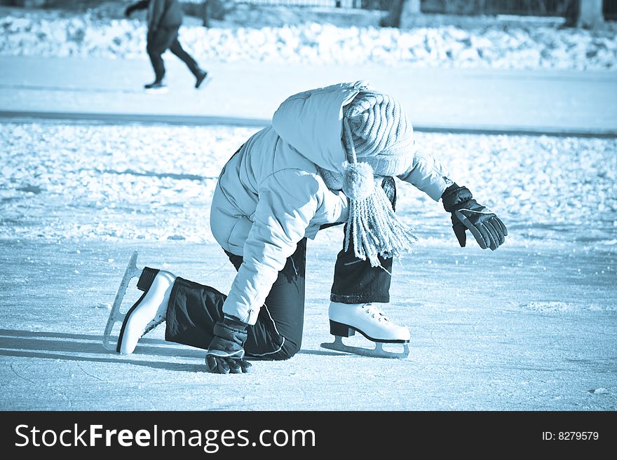 Girl on skates fell on the ice. Blue toning