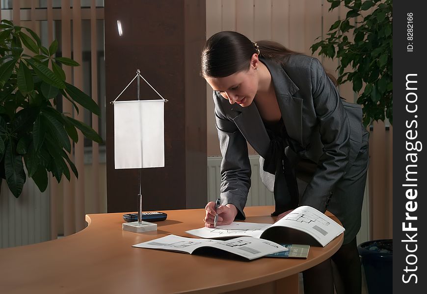 Young attractive business woman in a office environment makes notes in an album with drawings