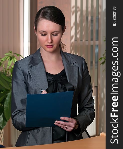 Portrait of a young attractive business woman with blue folder in a office environment. Portrait of a young attractive business woman with blue folder in a office environment