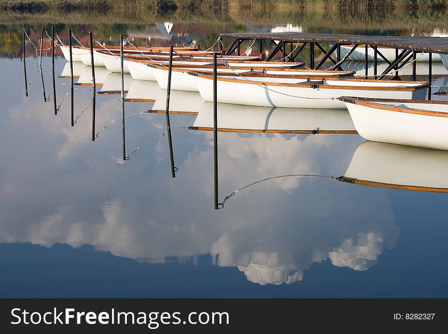 Water mirroring white boats and the cloudy sky.