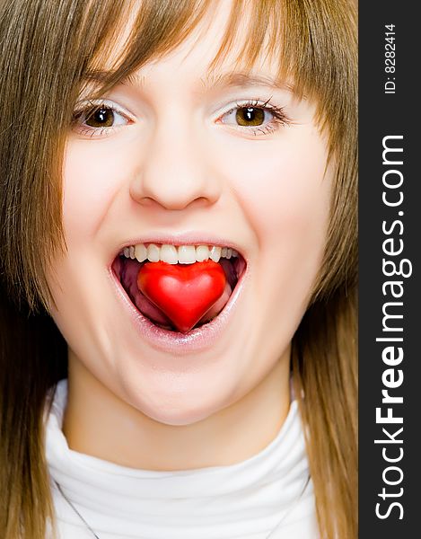 Young girl with heart-shaped candy in her mouth. Young girl with heart-shaped candy in her mouth