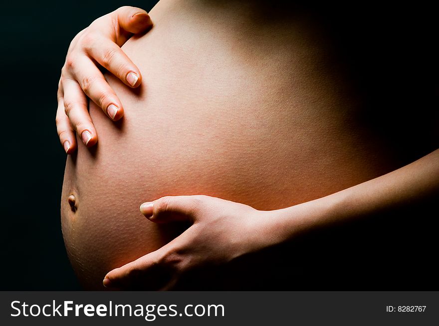 Close-up of pregnant woman holding hands over her belly