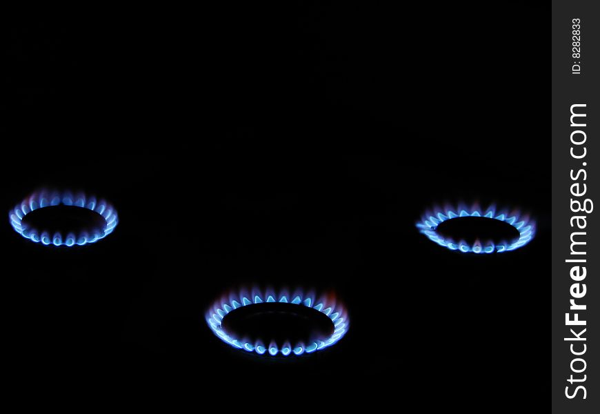 Blue flame of gas over black background