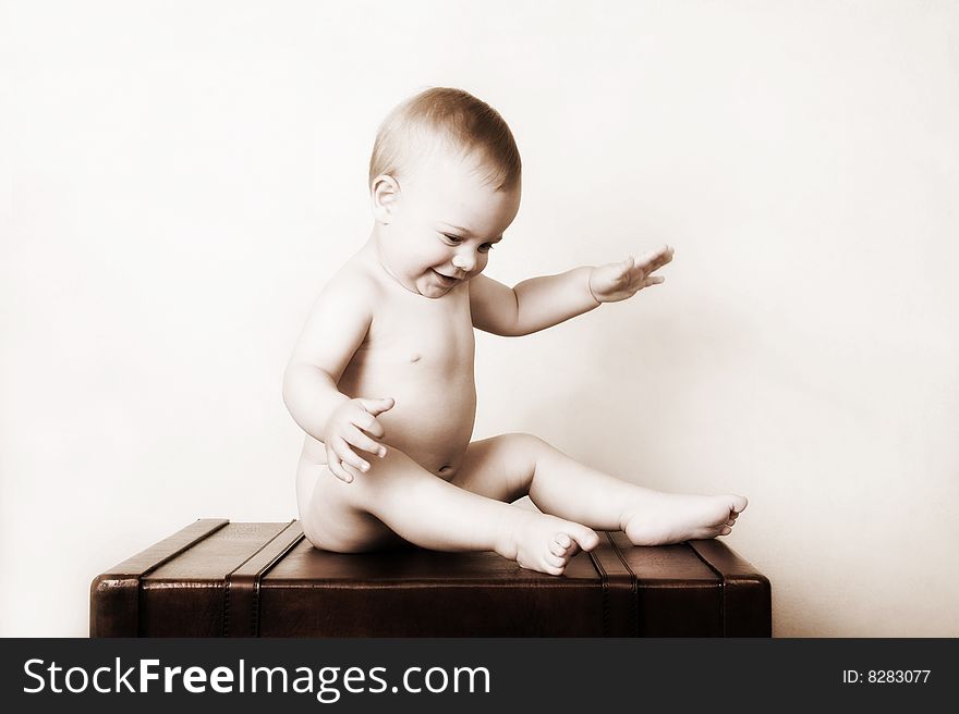 Young baby sitting on an old style suitcase