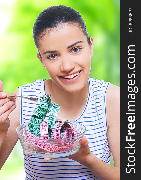 portrait of a young woman eating measuring tape with a fork. portrait of a young woman eating measuring tape with a fork