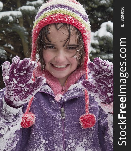 Young girl holding hands up while out playing in the snow. Young girl holding hands up while out playing in the snow