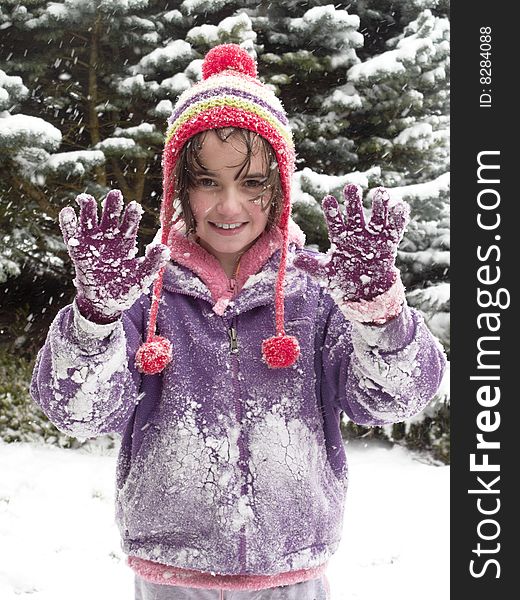 Young girl holding hands up while out playing in the snow. Young girl holding hands up while out playing in the snow