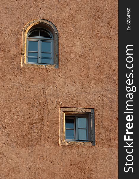 Two old windows on rough old wall