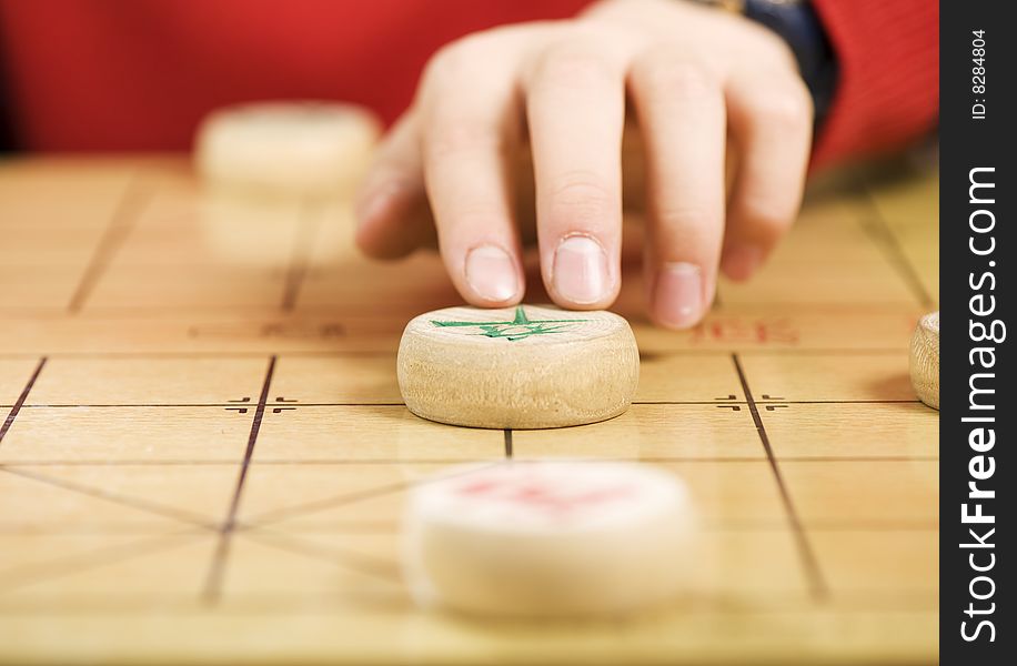 A boy is moving a piece of Chinese chess. A boy is moving a piece of Chinese chess.