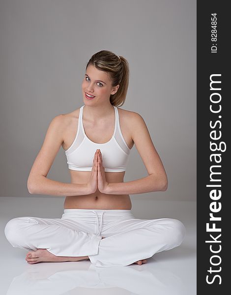 Fitness â€“ Young woman in yoga position on gray background