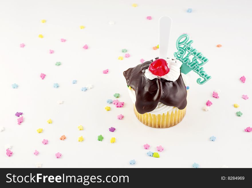 Happy Birthday Sundae Cupcake with fudge topping cherry and plastic spoon, with Happy Birthday decoration copy space