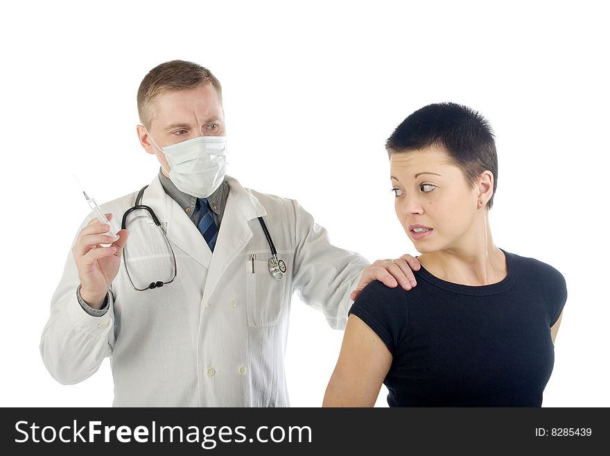 Doctor in gauze mask holds a frightened woman by her shoulder and prepares a syringe for an injection. Doctor in gauze mask holds a frightened woman by her shoulder and prepares a syringe for an injection