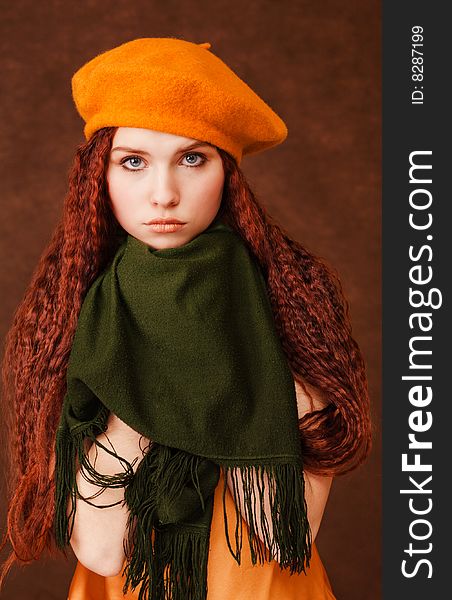 Young beautiful girl in orange beret on dark background. Young beautiful girl in orange beret on dark background