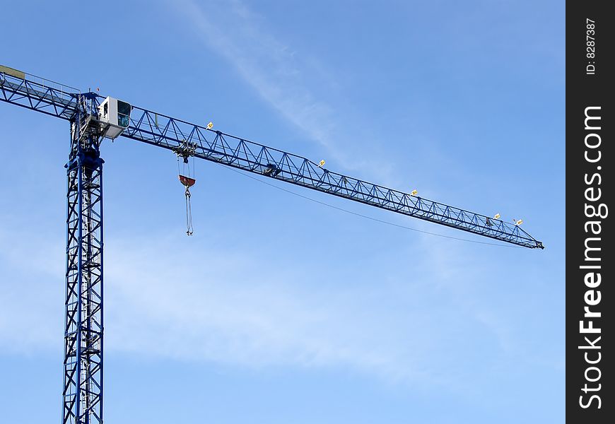 Construction crane at a construction site against the backdrop of blue sky
