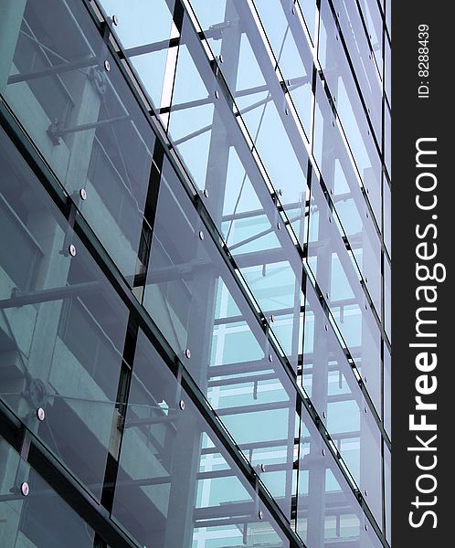 Glass construction with reflections. Blue light grey glass changing color from the sun. Concrete construction is seen behind the glass. Glass construction with reflections. Blue light grey glass changing color from the sun. Concrete construction is seen behind the glass.