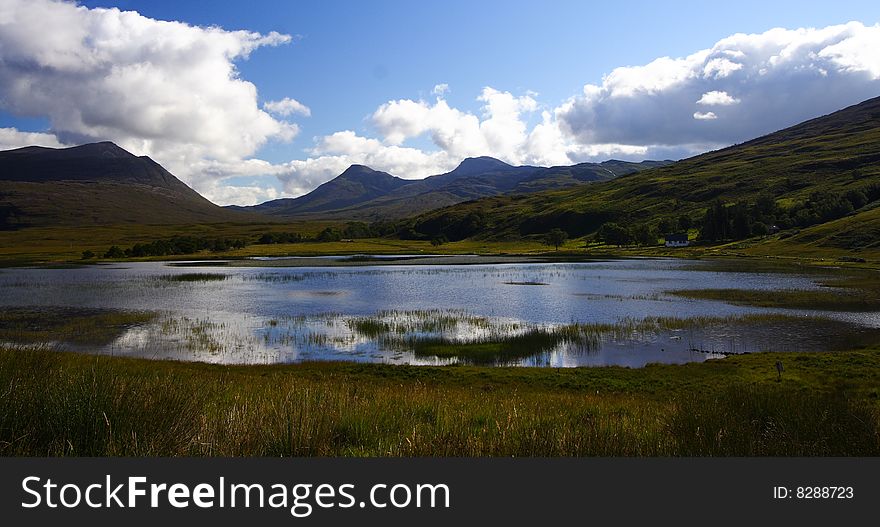 Superb loch in the highlands during summer, surrounded by mountains and hills.