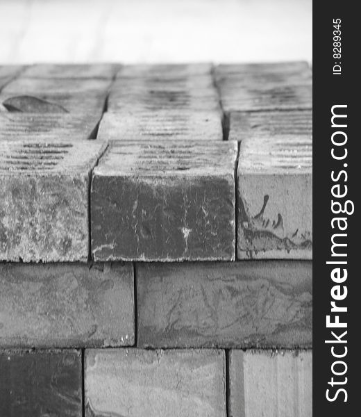 An up close black and white shot of bricks stacked up neatly on top of each . on the top you can see 4 bricks lying on there backs going length ways,  on the side you can see their sides as they are stacked on top of each other some are showing their sides others are showing their ends. An up close black and white shot of bricks stacked up neatly on top of each . on the top you can see 4 bricks lying on there backs going length ways,  on the side you can see their sides as they are stacked on top of each other some are showing their sides others are showing their ends