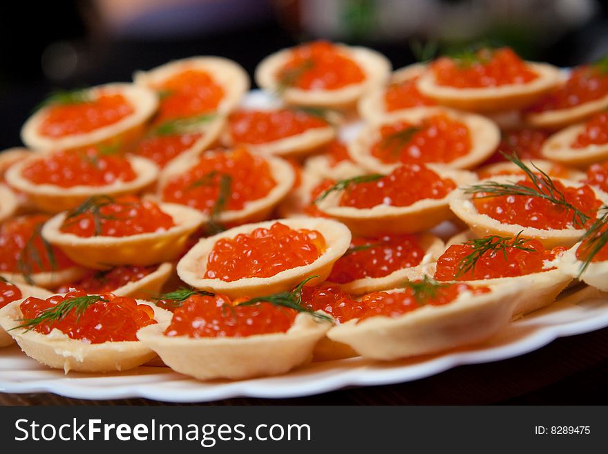 Tartlets with red caviar on a white dish