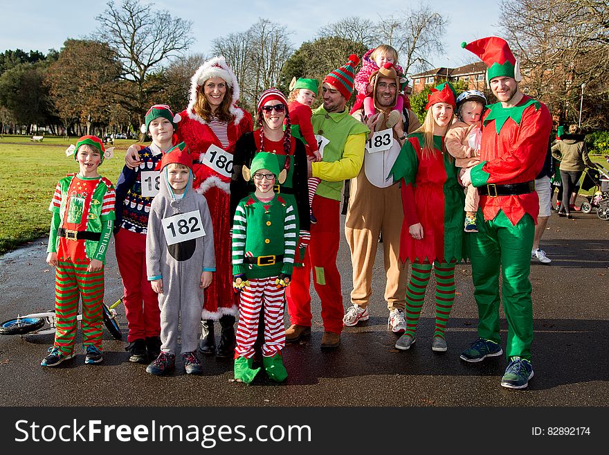 Group of adults and children dressed as elves standing on walkway on sunny day. Group of adults and children dressed as elves standing on walkway on sunny day.