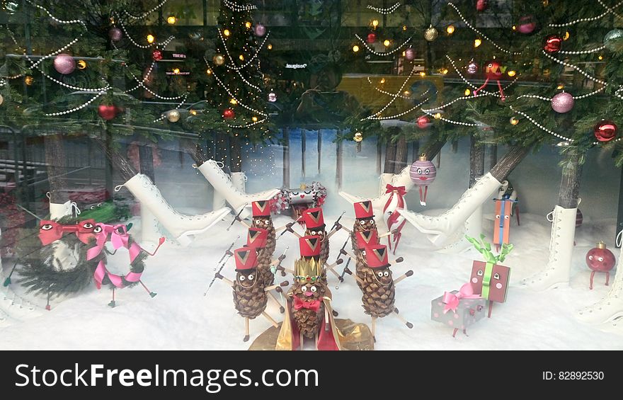 Christmas display with decorated pine cones, boots and ornaments on tree.