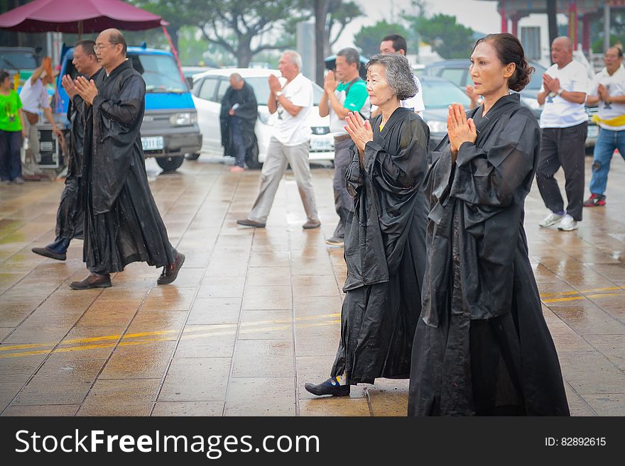 Asian mature men and women walking in rain on streets with hands folded in front. Asian mature men and women walking in rain on streets with hands folded in front.