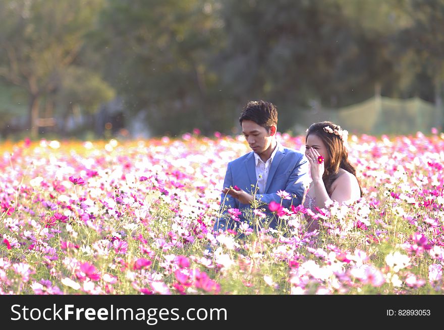 An Asian couple, man and woman, standing on a meadow with flowers. An Asian couple, man and woman, standing on a meadow with flowers.